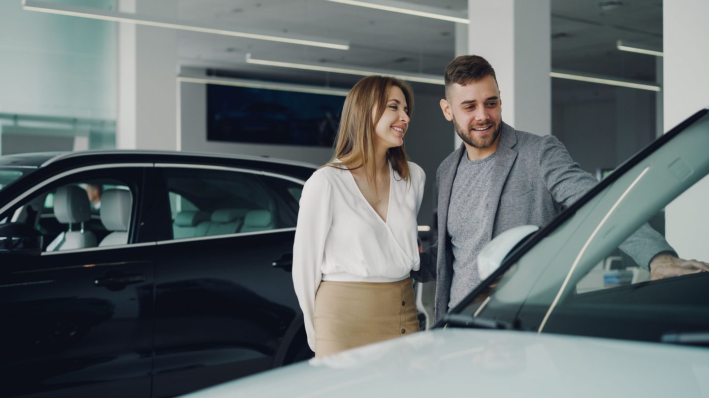Two people viewing a vehicle together inside a dealership showroom