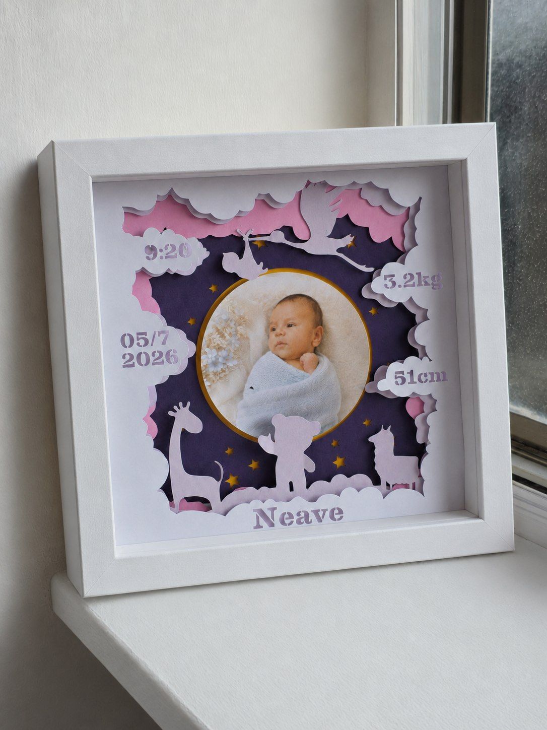Custom layered keepsake frame featuring a newborn photograph, birth details, paper clouds, stars, and animal silhouettes.