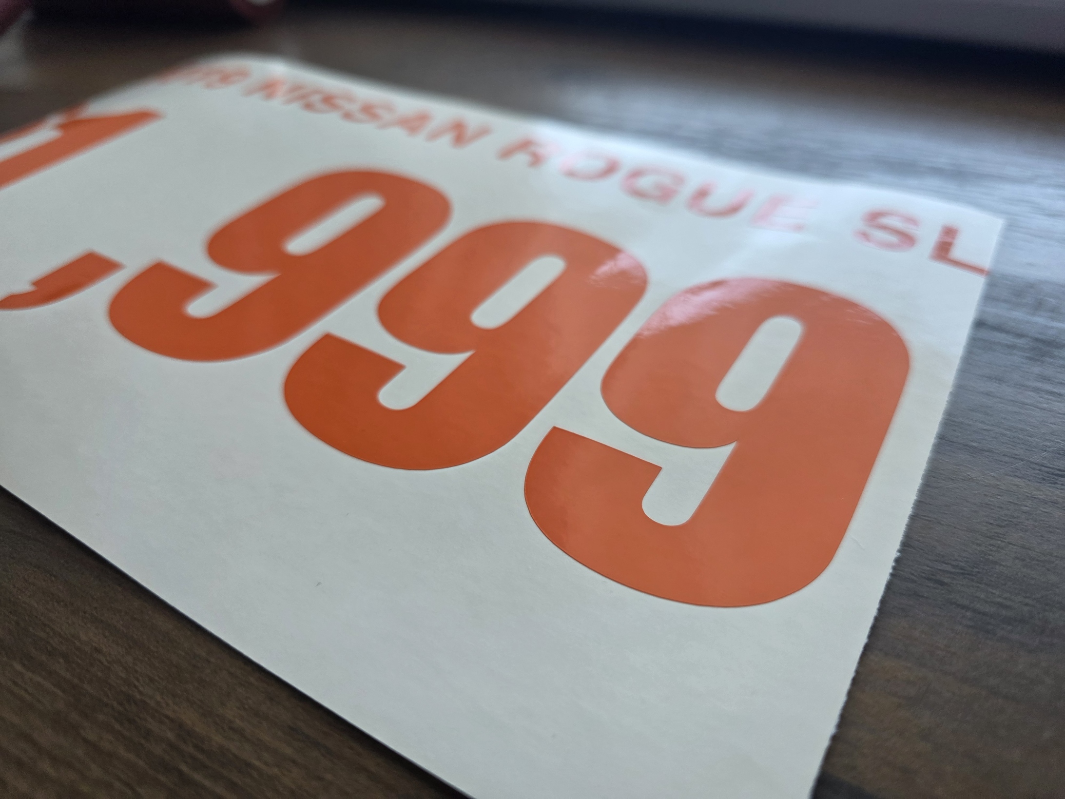 Close-up of an orange cut-vinyl price line prepared on white release backing