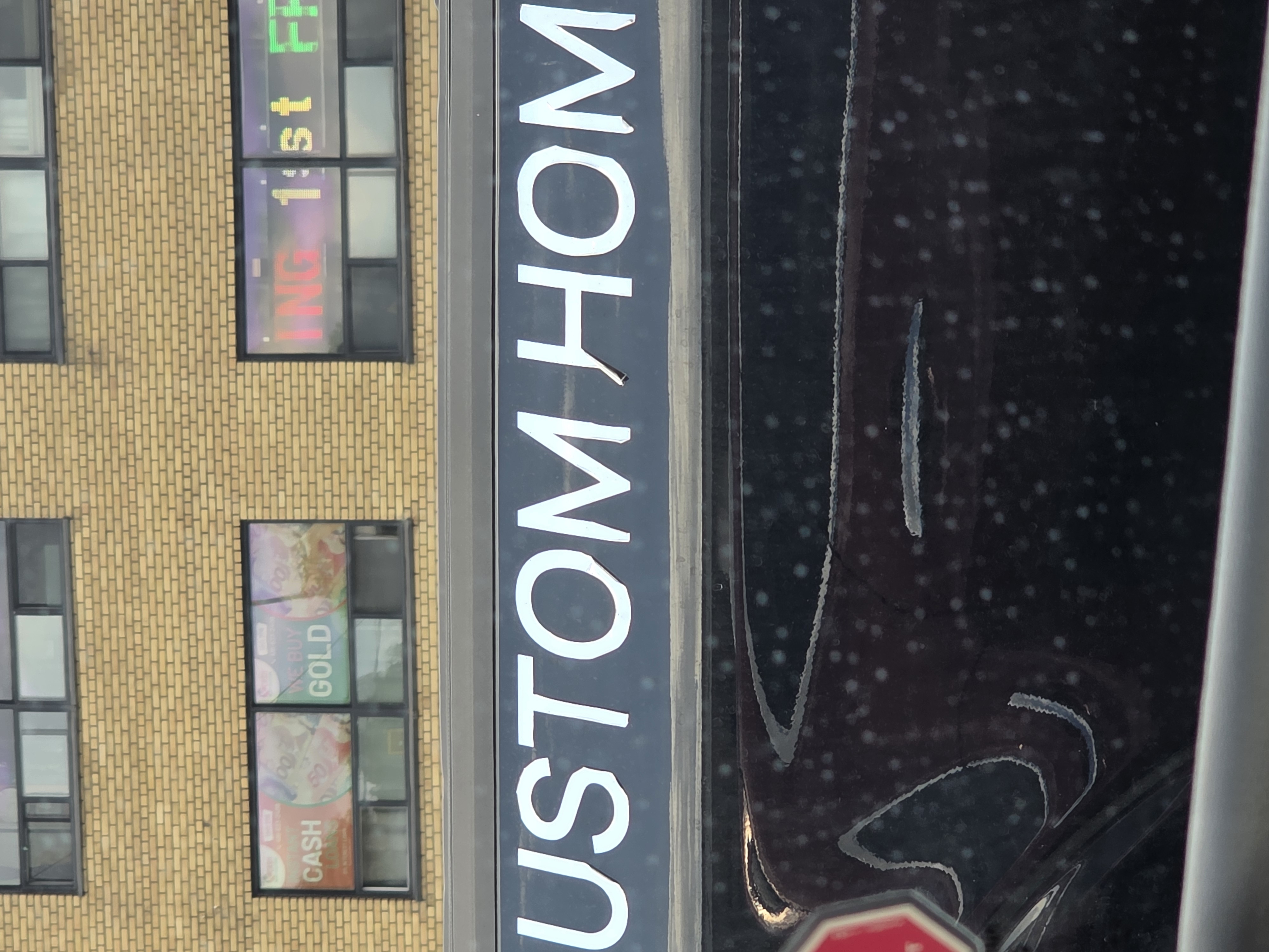Close-up of white vinyl vehicle lettering peeling away from a black vehicle