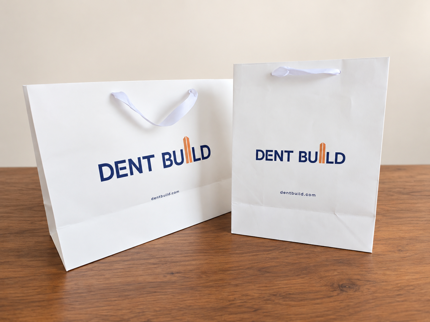 Dent Build branded white paper bags with ribbon handles in two sizes