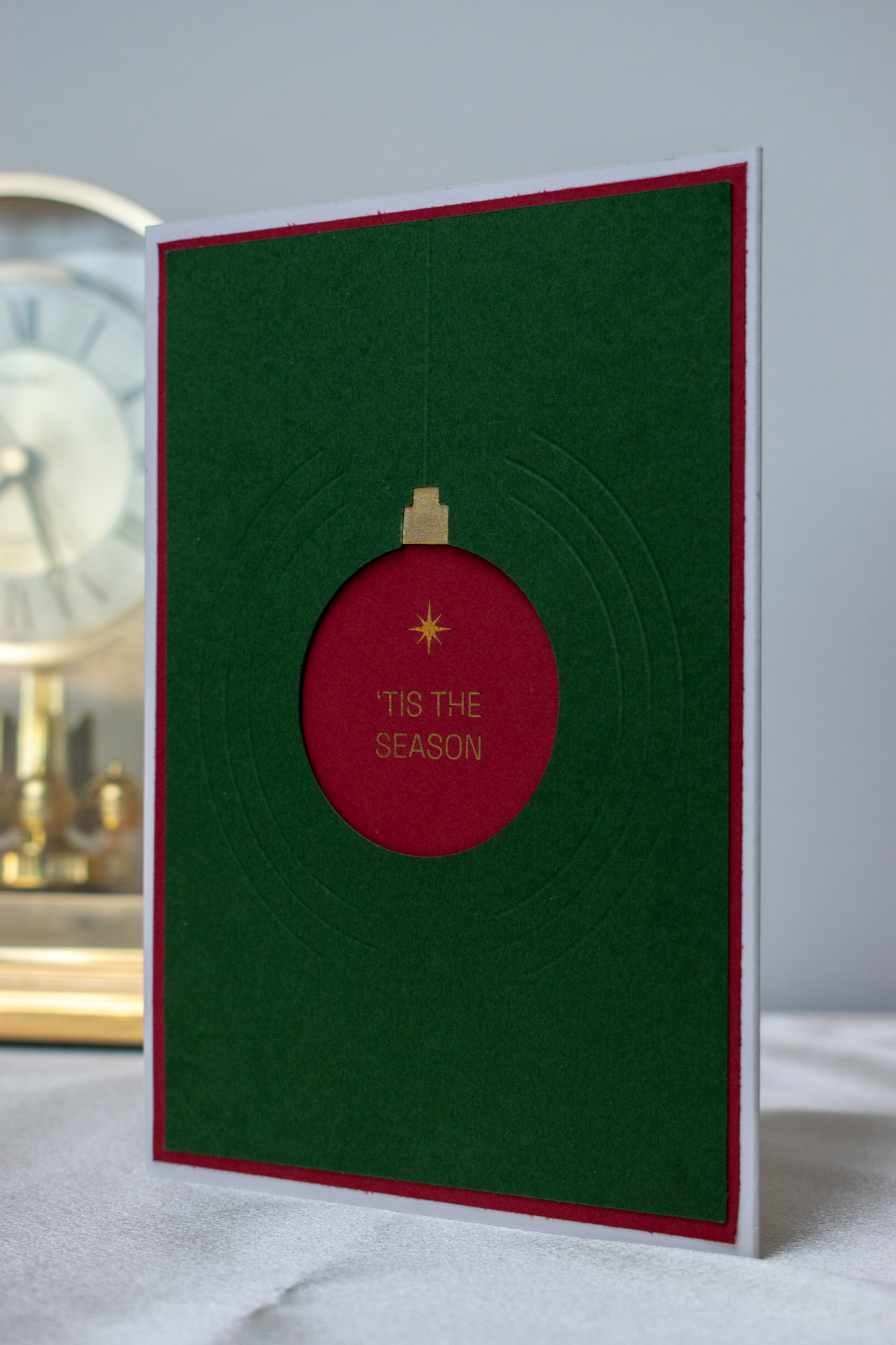 Close-up of scored concentric lines and a dimensional ornament on a green holiday card