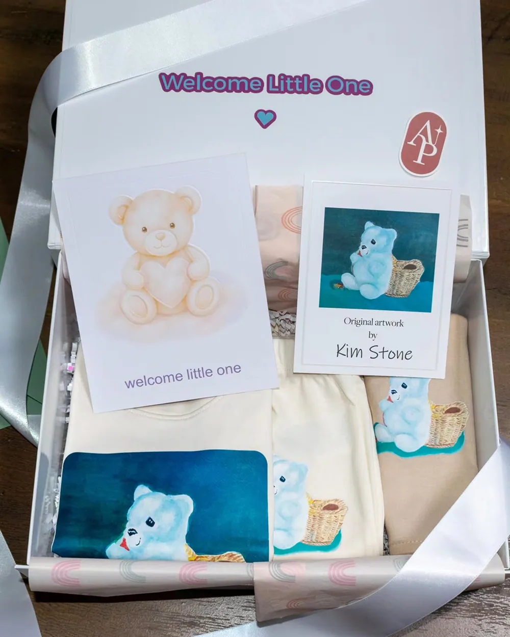 Welcome Little One gift box with a baby shirt, bib, keepsake card and packaging created from Kim Stone's original bear artwork