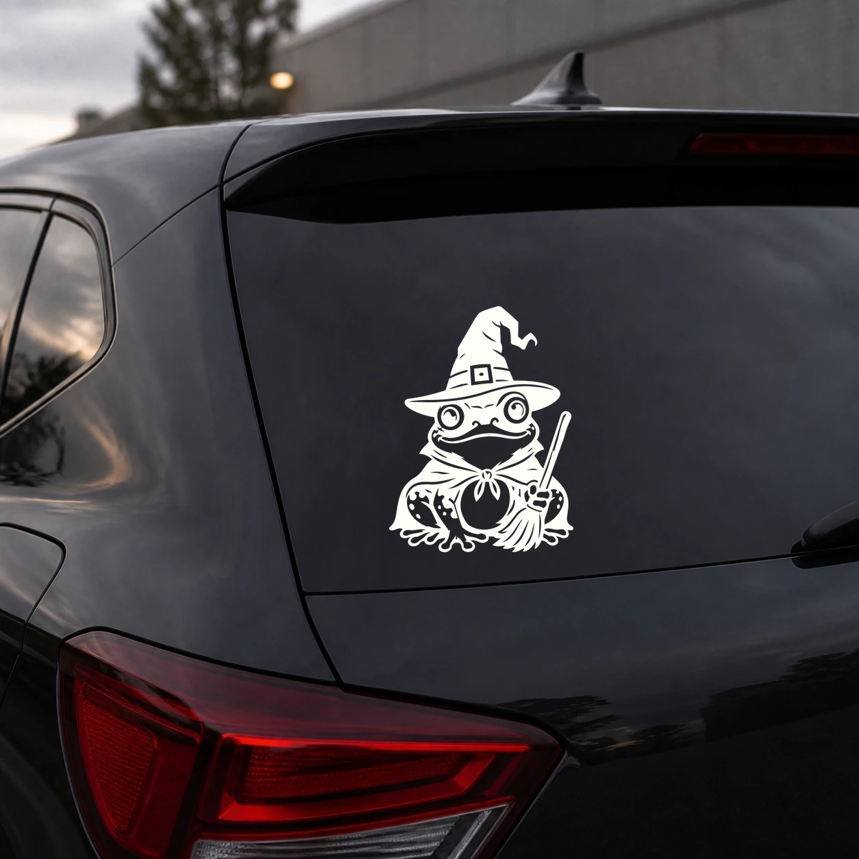Warm ivory frog witch decal on a dark vehicle rear window