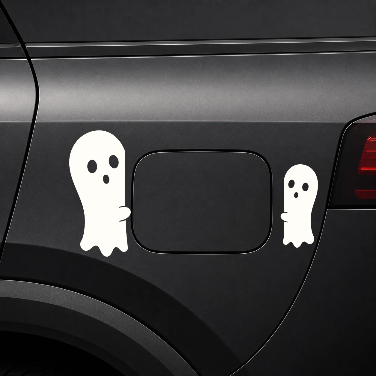 Warm ivory pair of ghost decals peeking from opposing edges of a dark vehicle fuel door