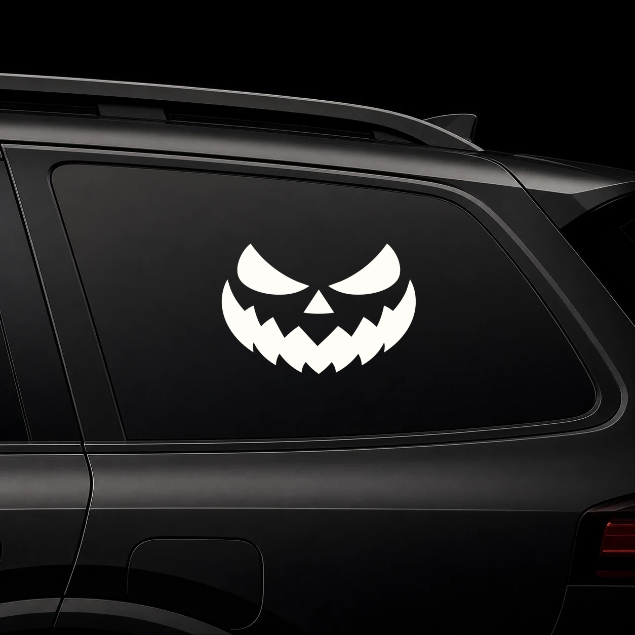 Warm ivory sinister jack-o’-lantern eyes and jagged mouth vinyl decal on dark glass