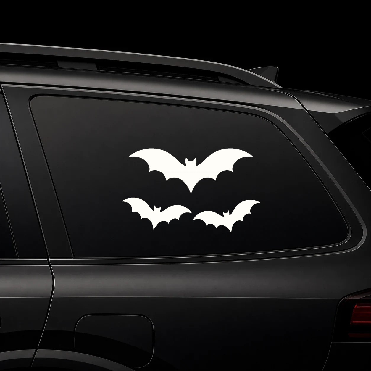 Three large bat decals on a dark vehicle rear side window