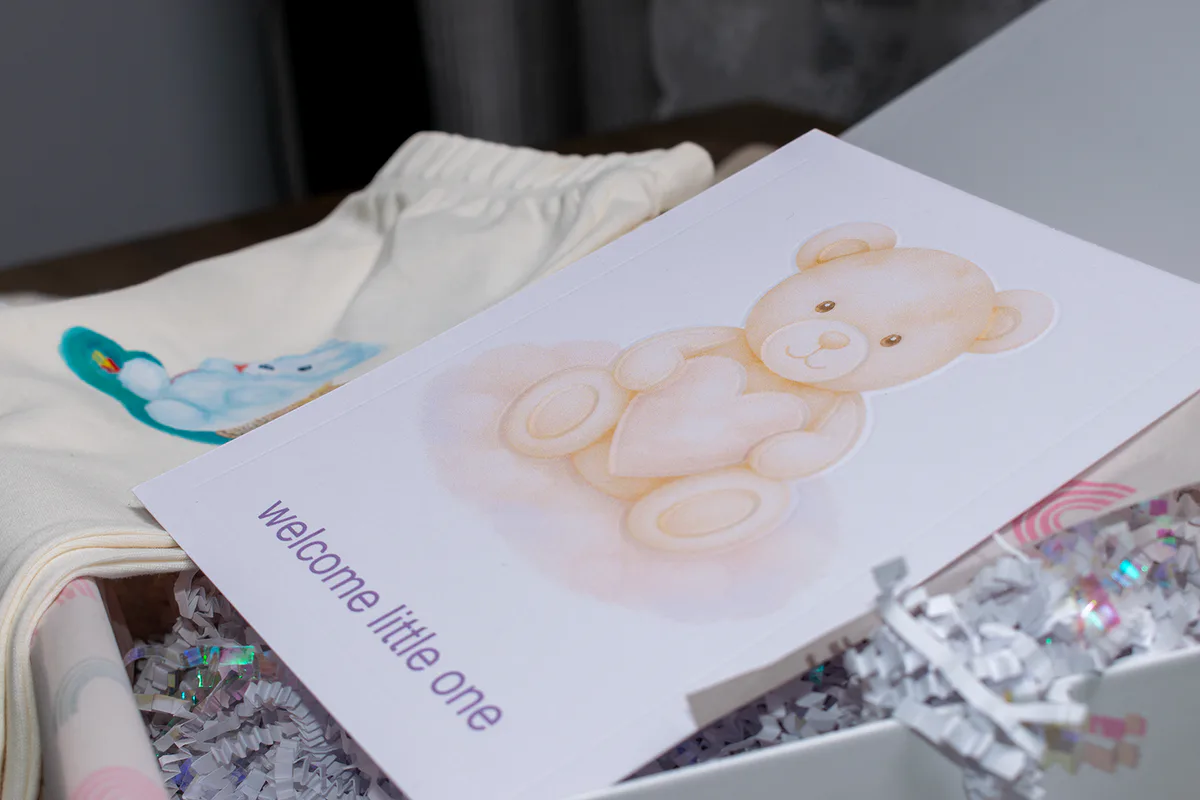 Handcrafted new baby card arranged with personalized apparel and gift-box details